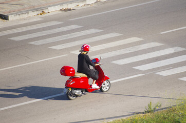 Girl with a red and white protective helmet riding a red  an Italian symbol