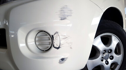 Scratches on white car after accident. Damaged on front bumper.
