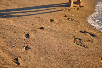 Footprints in the sand. The feet of the mother and child walk along the shore. Summer memories. Plzha by the sea. High quality photo