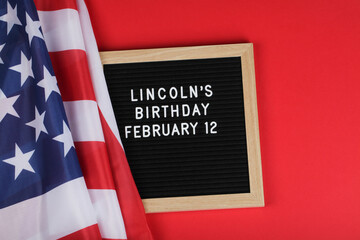 black letter board with text Lincoln's Birthday and American flag on red background.