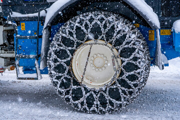 Closeup of a chained wheel of a snowy snow plow on the mountain ski resort in french Alps. High...