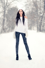 Winter brunette woman with long legs in warm sweater. Outdoor fashion portrait in the winter forest