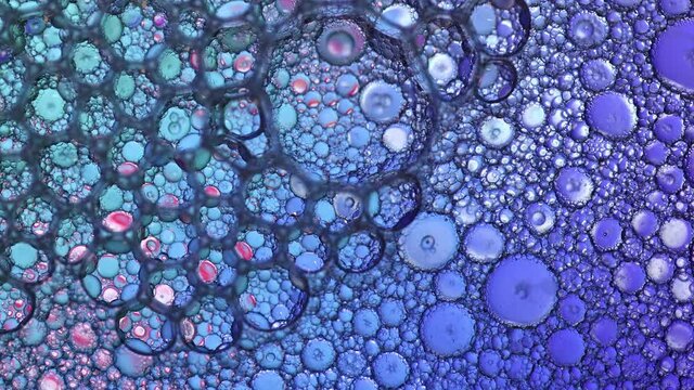 Macro of colorful bubbles popping in liquid mixture of water and oil.