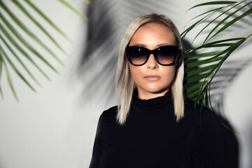 Close-up of woman with sunglasses with tropical palm leaves