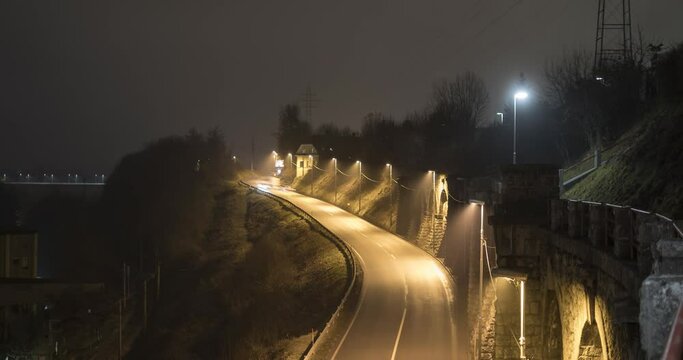 Night time lapse of cars driving on road. Famous stone wall in small town Kranj, Slovenia. Light trails from cars. Zoom in