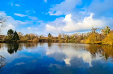 Panoramic view of a lake, called Altwasser in German.
Peaceful landscape with trees on the shore and cumulus clouds in the blue sky. Neuburg am Rhein, Rhineland-Palatinate, Germany