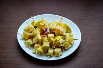 Canapes with cheese, lemon and marmalade on a white plate. Wooden table background. Fresh and healthy food. Diet