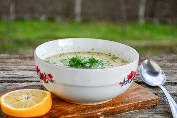 Home made chicken soup with noodles ,parsley and vegetables in white bowl . Healty soup
