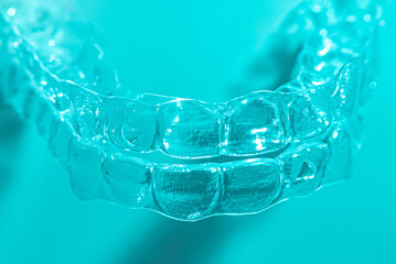 Invisible dental teeth brackets tooth aligners on blue background. Plastic braces dentistry retainers to straighten teeth.