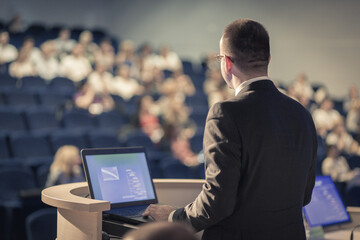 Speaker giving a talk on corporate Business Conference. Audience at the conference hall. Business...