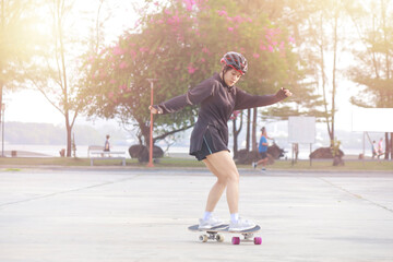 Asian women on skates board outdoors on beautiful summer day. Happy young women play surfskate at park on morning time. Sport activity lifestyle concept