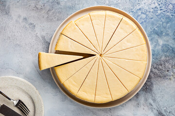 Classic New York cheesecake on light blue concrete background, top view