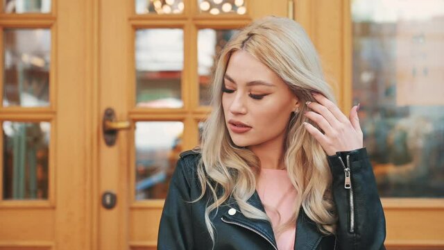 Portrait of pretty young blonde woman smiling in makeup with lipstick looking at camera outdoor