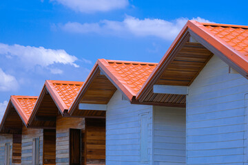 Perspective side view of knockdown wooden houses made of remaining materials used against white cloud and blue sky background, reuse and upcycle concept