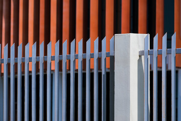 Side view of gray steel fence in sharp designed with blurred background of modern office building