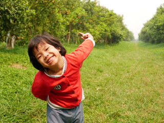 Little smiling baby girl, 3 years old, enjoys visiting an orange orchard / farm - outdoor activity for kid