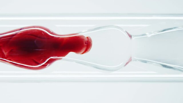The blood passes through filters in the laboratory. The thick red ink is mixed with water in a glass laboratory tube. Red thick liquid. Perfumery products. Passion. Adrenalin.