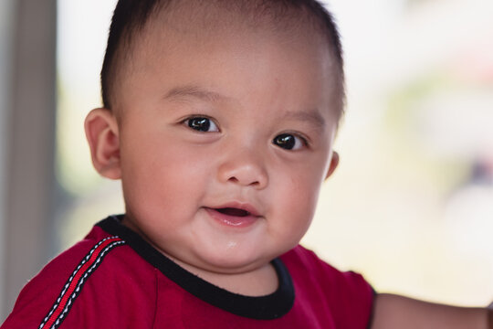 Portrait of adorable expressions of Asian little baby on nature background and day light with copy space,Cute boy, 7 months old, crawling age, good smile and good mood. Healthy, big black eyes.