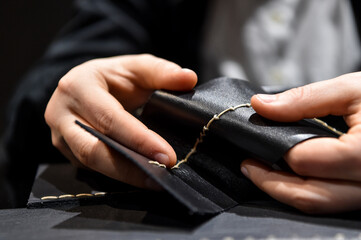 A leather craftsman works with leather. Sews leather goods. Use needle and thread for sewing.  Making things handmade..