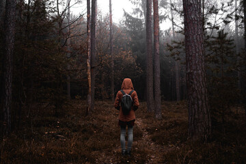 Girl with backpack from behind in the woods