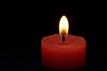 burning red candle on black background