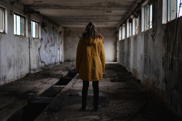 Girl with dreadlocks from behind in the old building