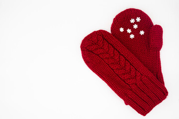 A knitted red mittens with white snowflakes on a white background, isolated. Concept of Christmas, winter, love. Care and Valentines day. Copy space