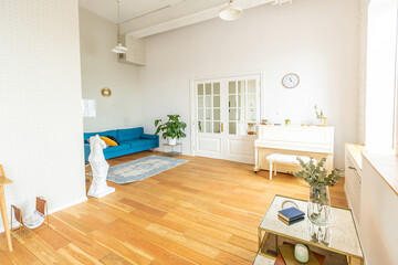 the interior of the study in the style of a loft. Brick wall. wooden flooring. large bright room with a seating area. sofa and piano