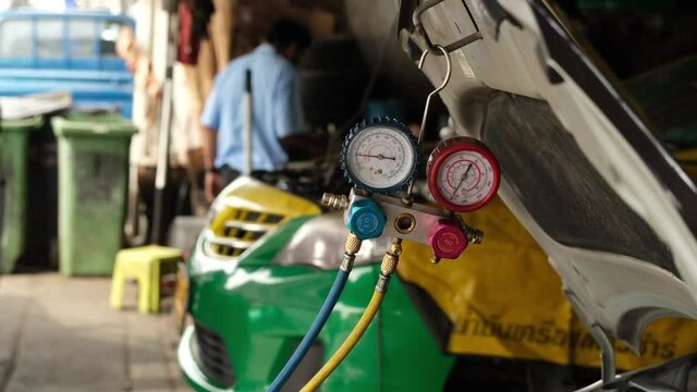 The maintenance technician is checking the car's air conditioner