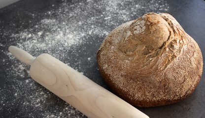Fresh baked round bread made of whole wheat.  Dark grey background with copy space. Top view photo of homemade bread.