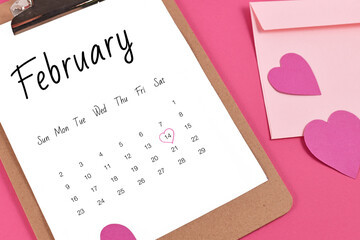 February calendar sheet with Valentine's Day on the 14th marked with heart surrounded by hearts and love letter on pink background