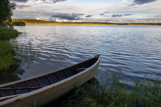Old rowing boat at the lake with forest landscape in background under cloudy sky, Kuusamo.,Lapland, Finland