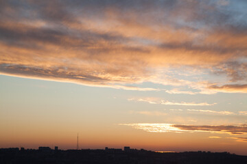 Naklejka premium Dramatic sunset sky with cityscape silhouette