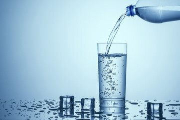 Clean drinking water is poured from the bottle into a clear glass.