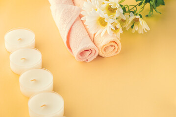 candles, towels and flowers on a yellow surface