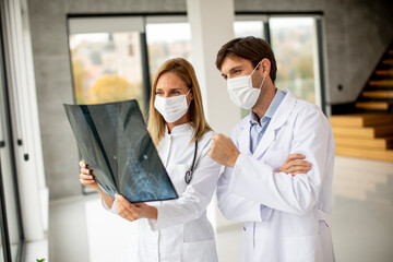 Team of doctors with protective facial masks examining xray