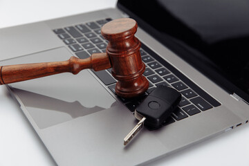 Judge gavel and car keys on laptop computer keyboard. Symbol of law, justice and online car auction.