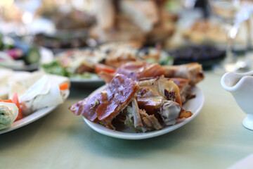 Dish with roasted young pig. Food table background.