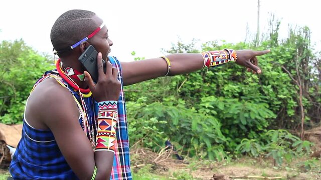 Maasai man on phone pointing his finger at subject of interest