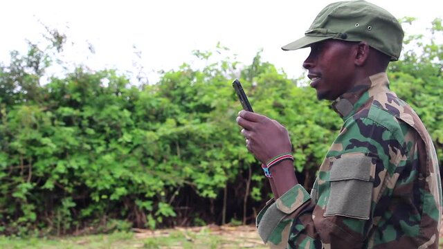 African militant guerilla texting on phone side angle