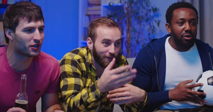 Cheerful mixed-races joyful men friends watch sport channel soccer together at home drinking beer with snacks having fun cheering for fav team watching football match on TV in evening Close up concept