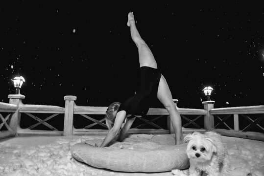 The girl shows a gymnastic exercise against the background of the night sky.