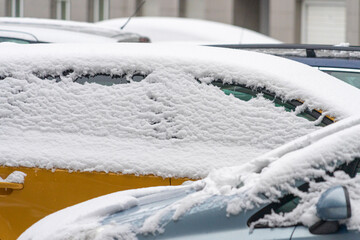 Cars covered with snow parked in the yard of residential apartments house