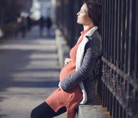 Happy pregnant young woman portrait holding her belly outdoors in the city - 403654402