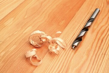 Drill and shavings isolated on a wooden board