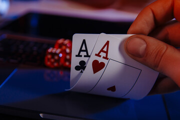 Dices and cards for poker in hand on laptop, online poker concept.