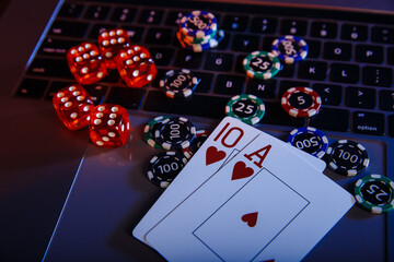 Fototapeta na wymiar Casino play online theme. Playing chips, cards and dices on laptop close-up.