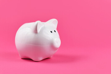White porcelain piggy bank for saving money on pink background