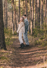 Naklejka na ściany i meble a couple walks in a pine forest in the tropics a guy holds a girl's hand while she looks into the frame
