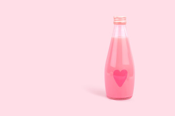 A small glass bottle with a heart painted on it and a pink milk drink copy space. Berry Milk Shake. A drink of love.